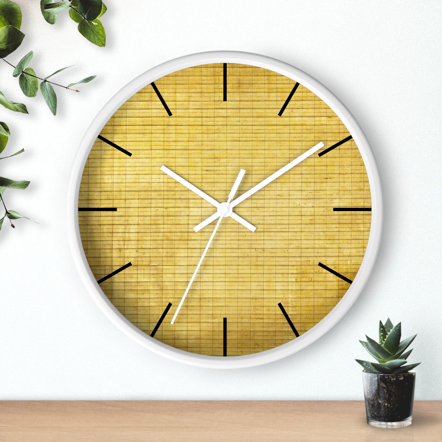 a white clock with a yellow face next to a potted plant