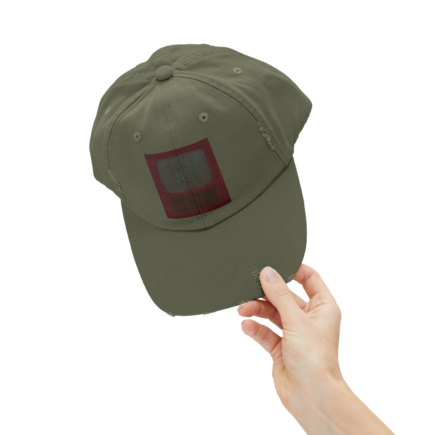 a hand holding a green hat with a red square on it