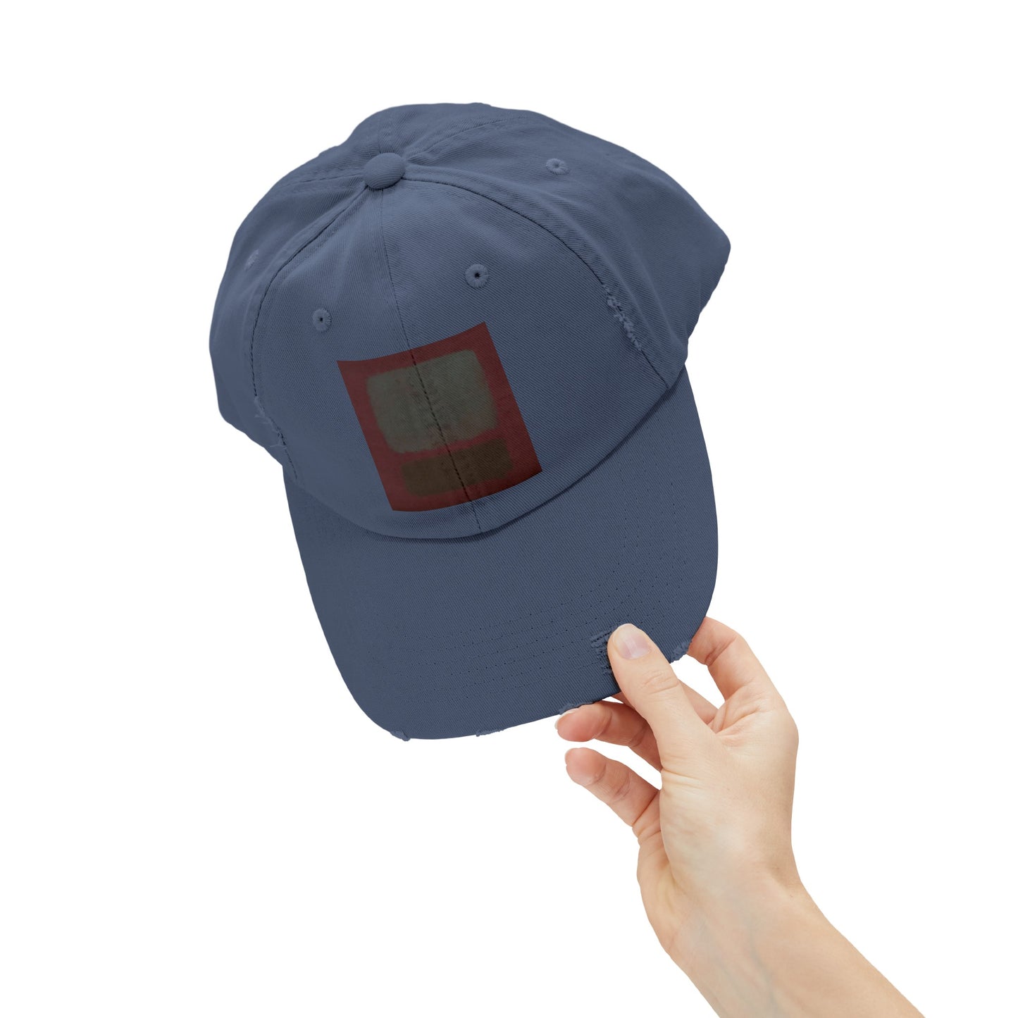 a hand holding a blue hat with a red square on it