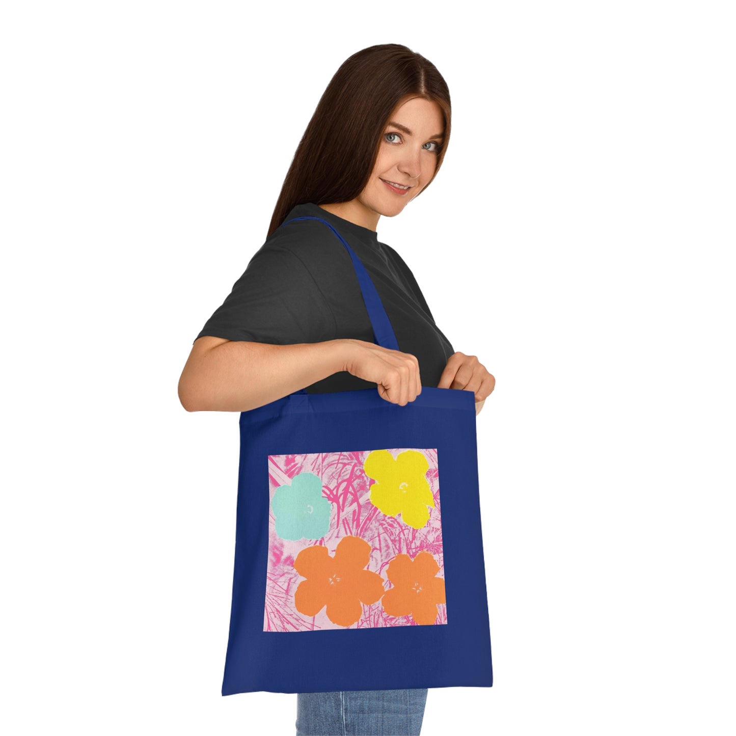 a woman holding a blue tote bag with flowers on it