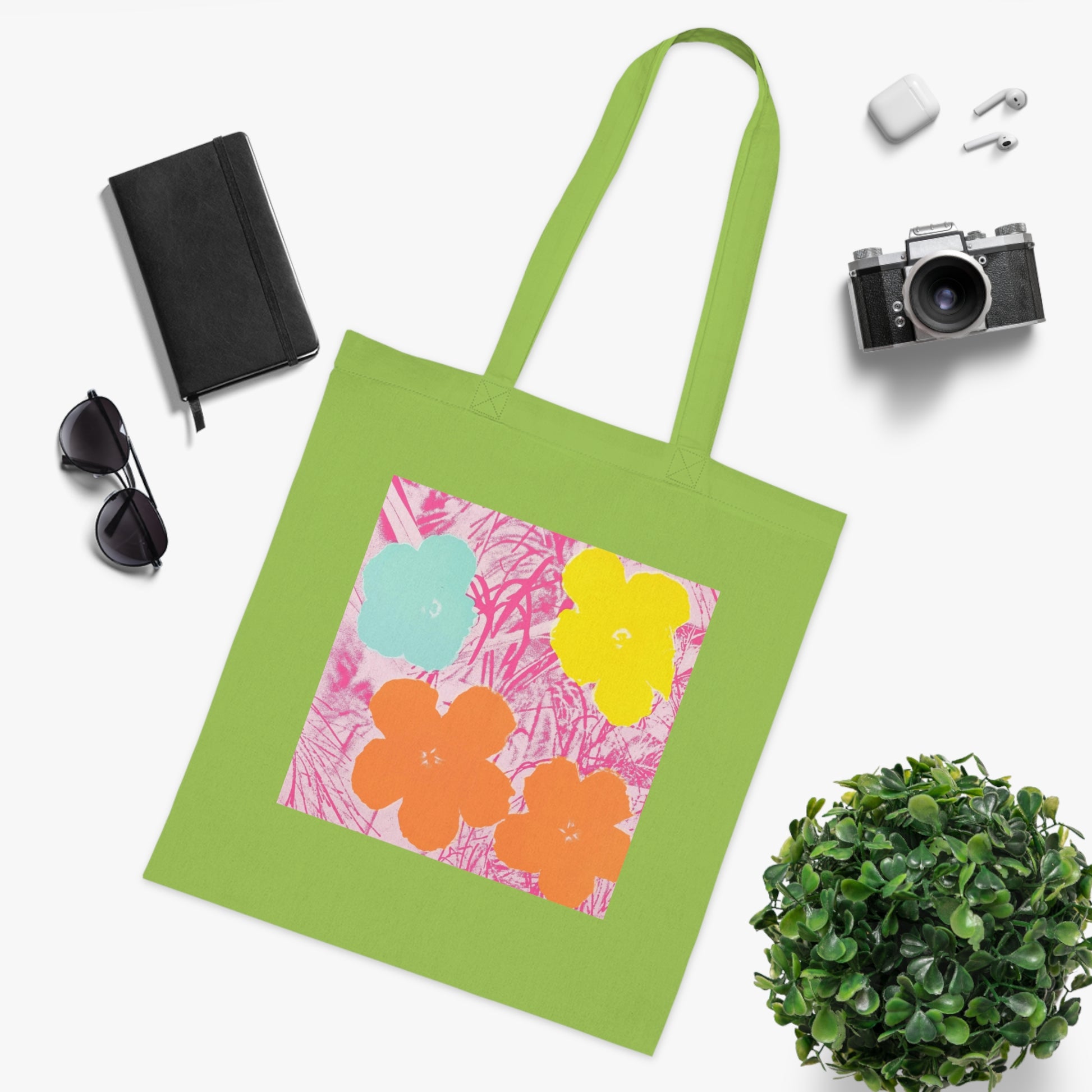 a green tote bag sitting next to a potted plant