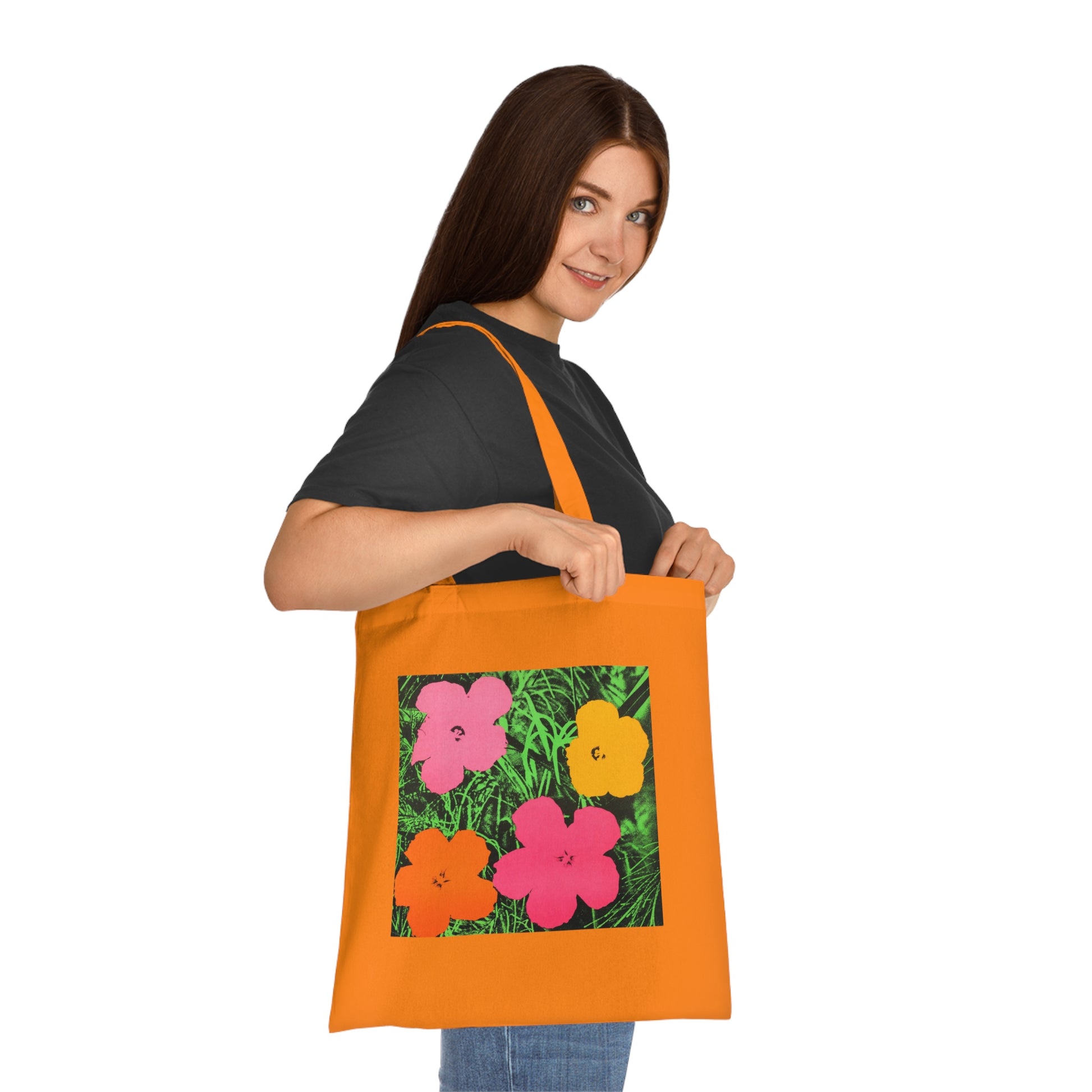 a woman holding an orange tote bag with flowers on it