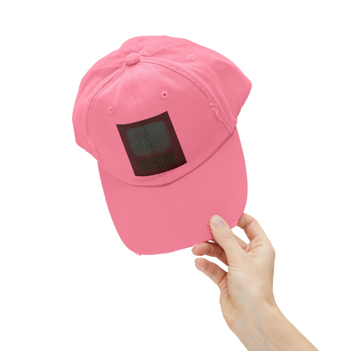 a person holding a pink hat with a black square on it