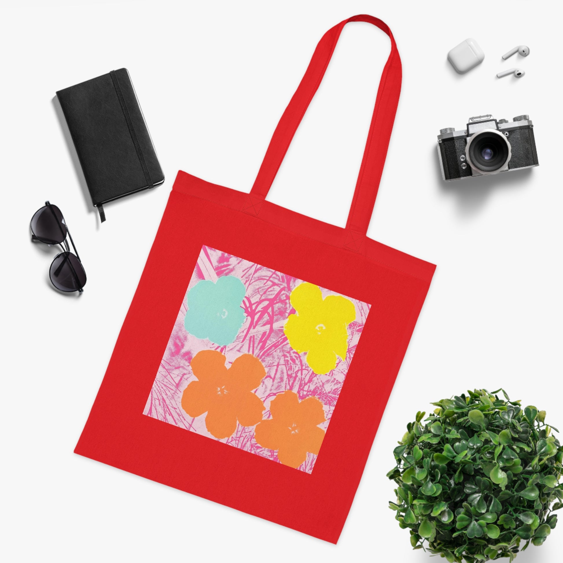 a red tote bag sitting next to a potted plant