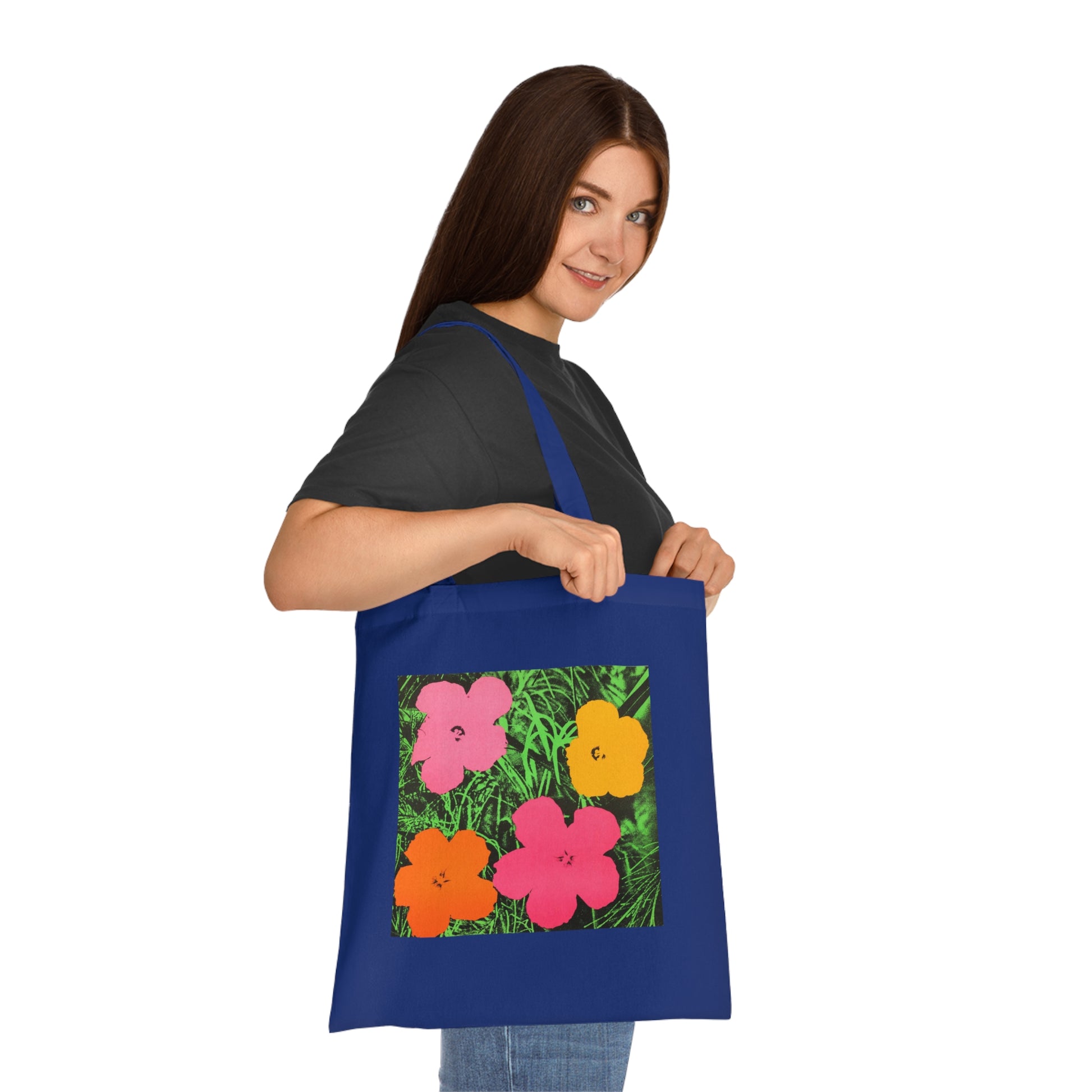 a woman holding a blue tote bag with flowers on it