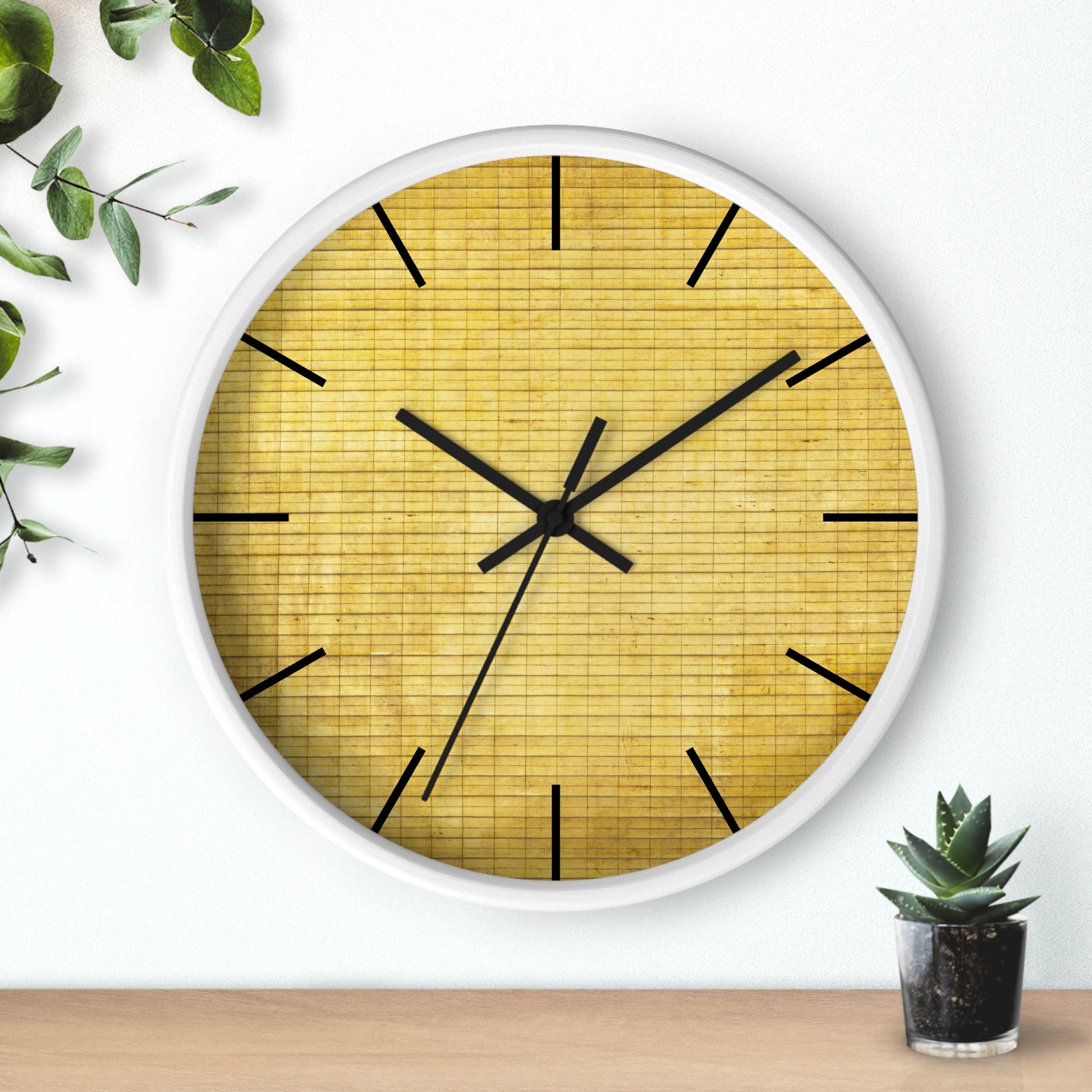 a white clock with a yellow face next to a potted plant
