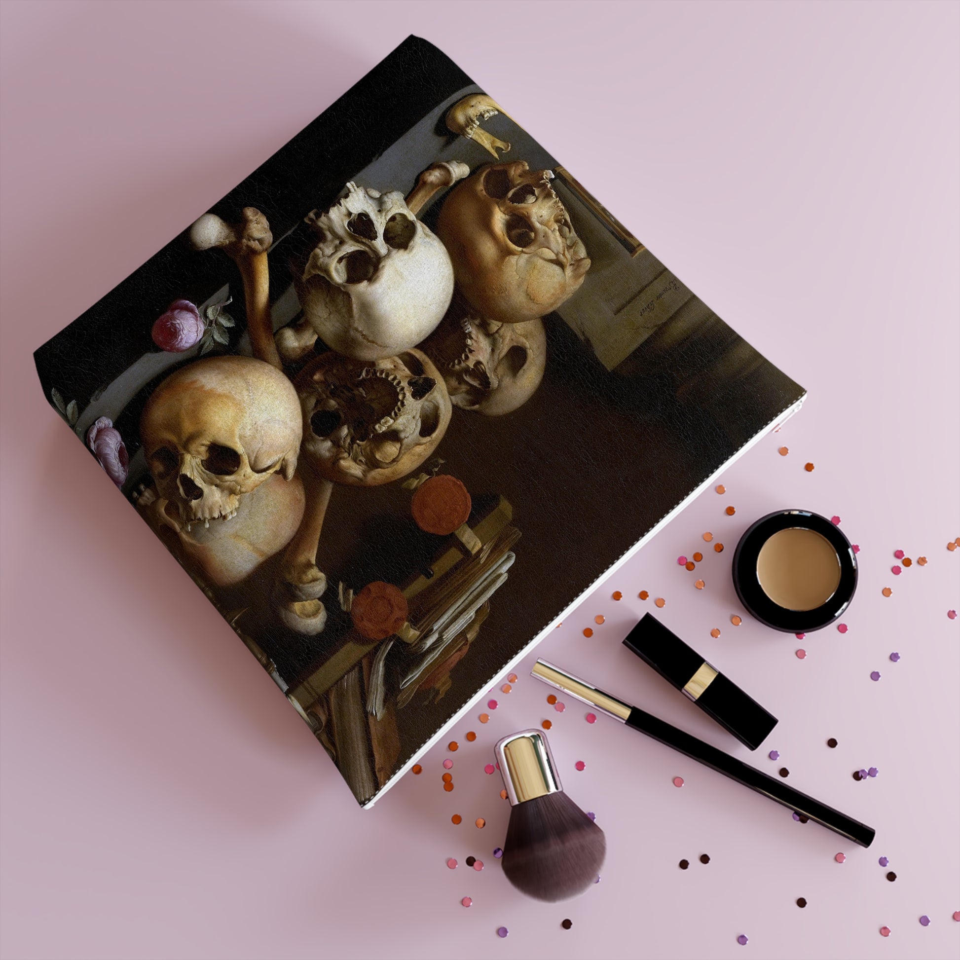 a picture of a group of skulls on a table next to a bottle of makeup
