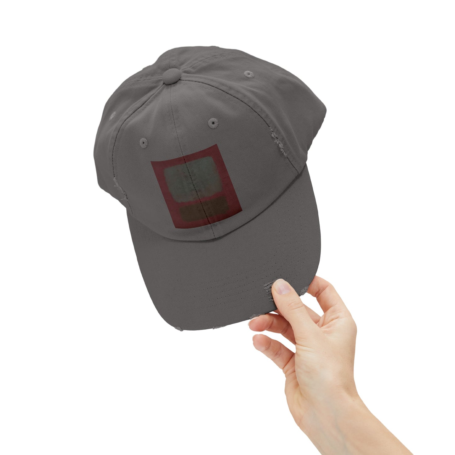 a person holding up a gray hat with a red square on it