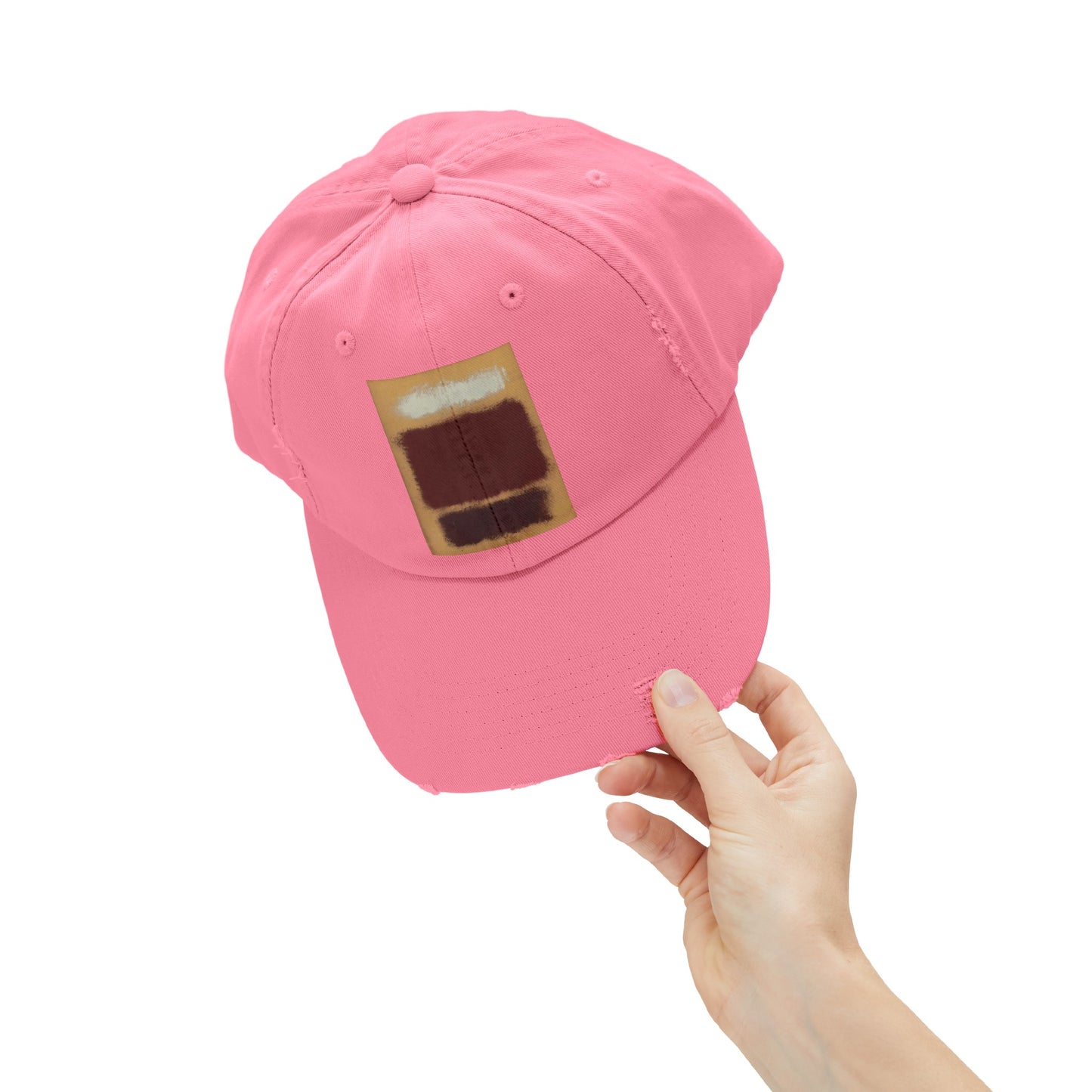 a person holding a pink hat with a brown patch on it