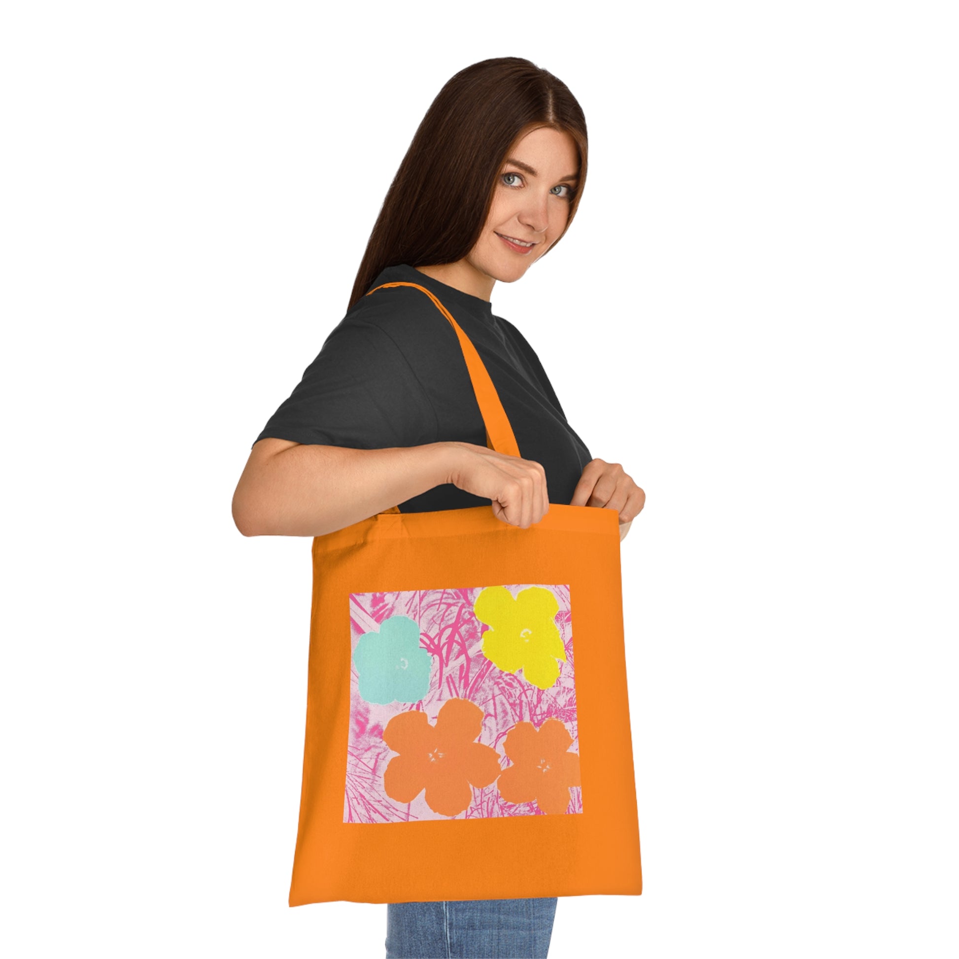 a woman holding an orange tote bag with flowers on it