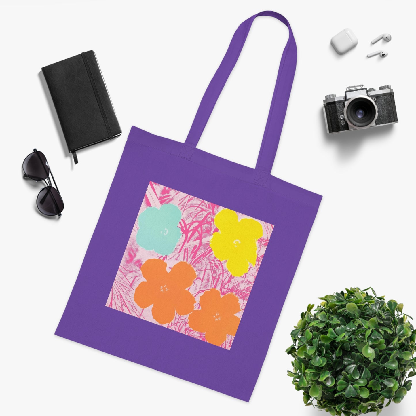 a purple tote bag sitting next to a potted plant