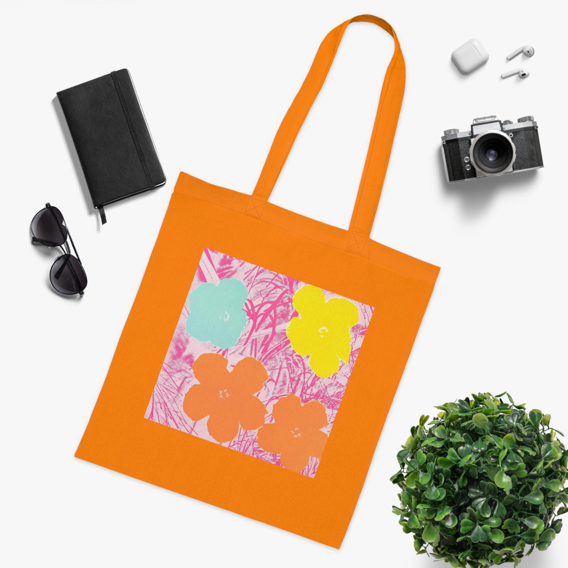 an orange tote bag sitting next to a potted plant